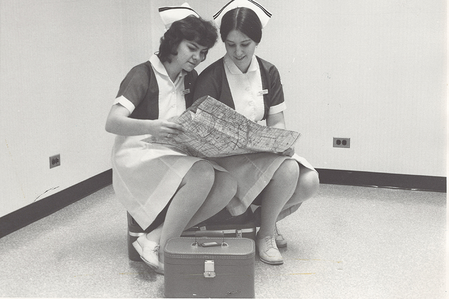 Nurses sitting on a suitcases looking at a map